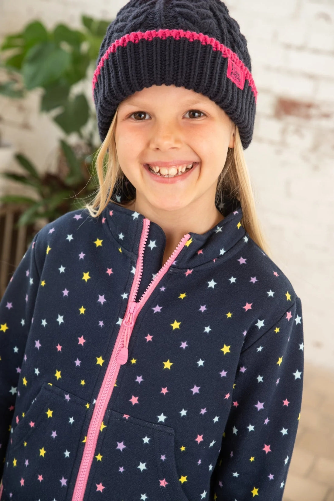 Kids Ava sweatshirt from Lighthouse in Navy with full zip, multicoloured star print, tummy pockets and elasticated cuffs and bottom hem.