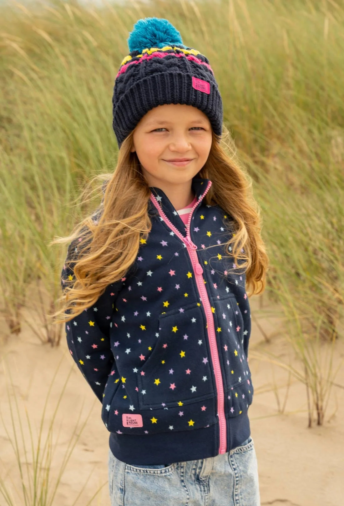 Lighthouse kids Ava full zip sweatshirt in Navy with multicoloured star print, with tummy pockets and small Lighthouse logo patch.