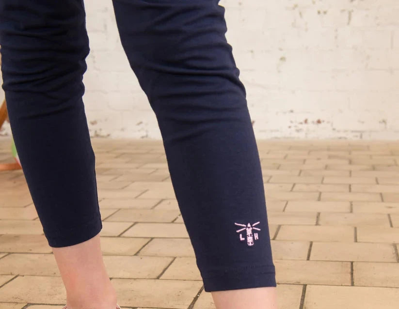 close up of the bottom of navy leggings  with a sewn on pink lighthouse logo 